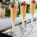 Three Visions heavy weight clear plastic champagne flutes filled with raspberries on a table.